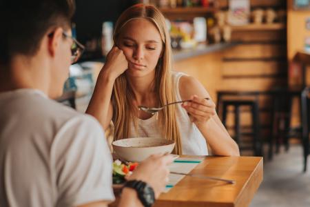 Vrouw aan tafel zichtbaar gespannen tijdens maaltijd, met hoofd in hand